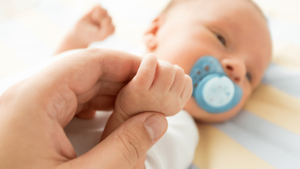 Newborn holding his parents' hands.