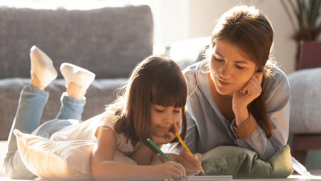 Mom and a girl toddler working with color pencils on a notepad, engaged in a creative activity together.