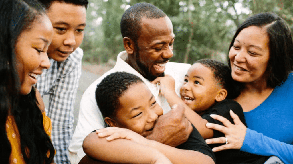 Happy black family laughing and holding each other close.