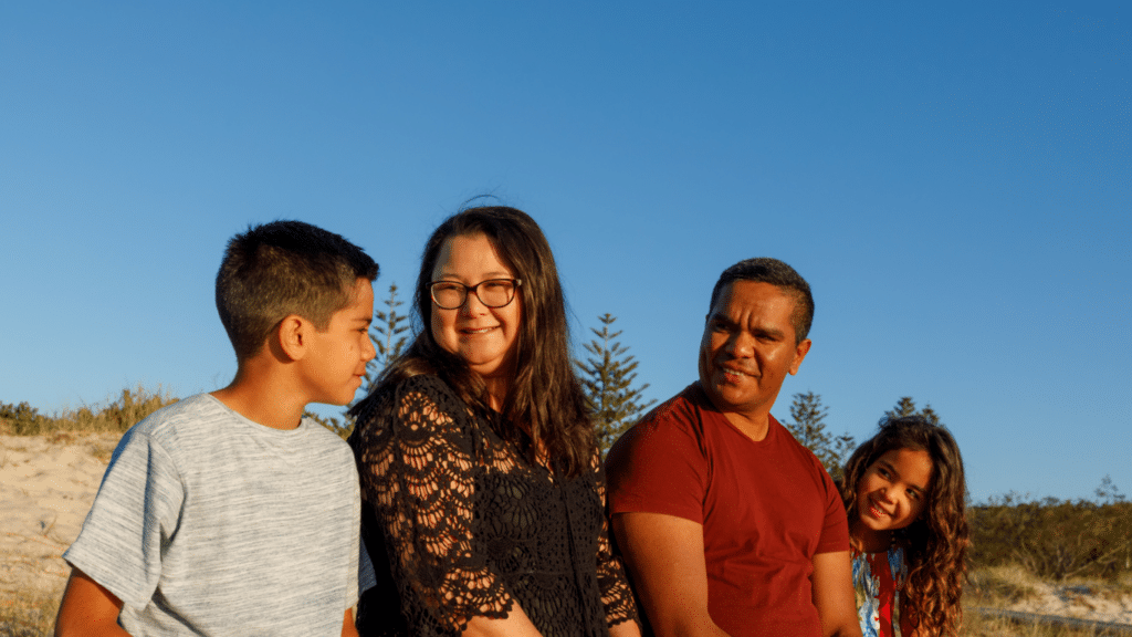 A young boy, a girl and a couple seated together, all with tanned skin and a smile on their faces.