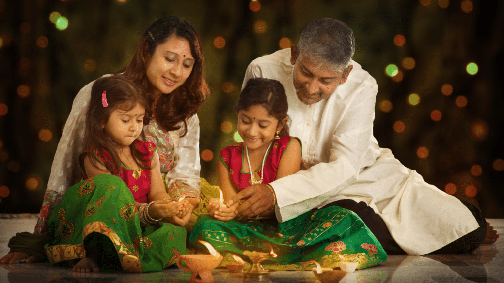 An Indian family with two little girls and their parents celebrating the festival of Diwali, joyfully holding diyas (traditional oil lamps).