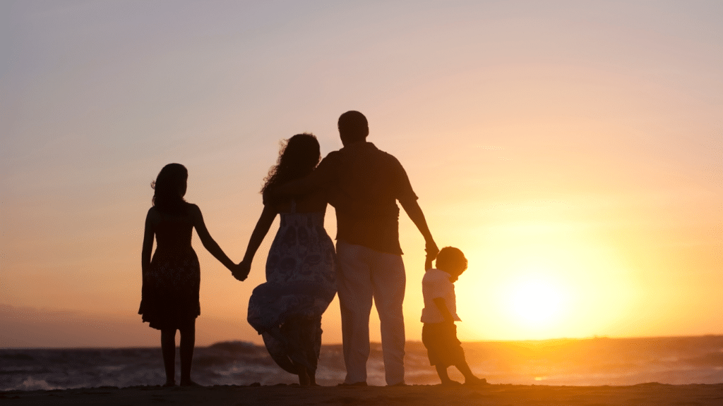 A shadow of family of four with sun setting in the background.