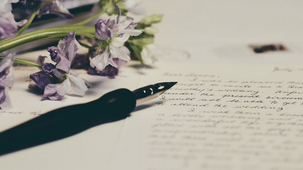 Image of a pen and letter along with purple flowers.