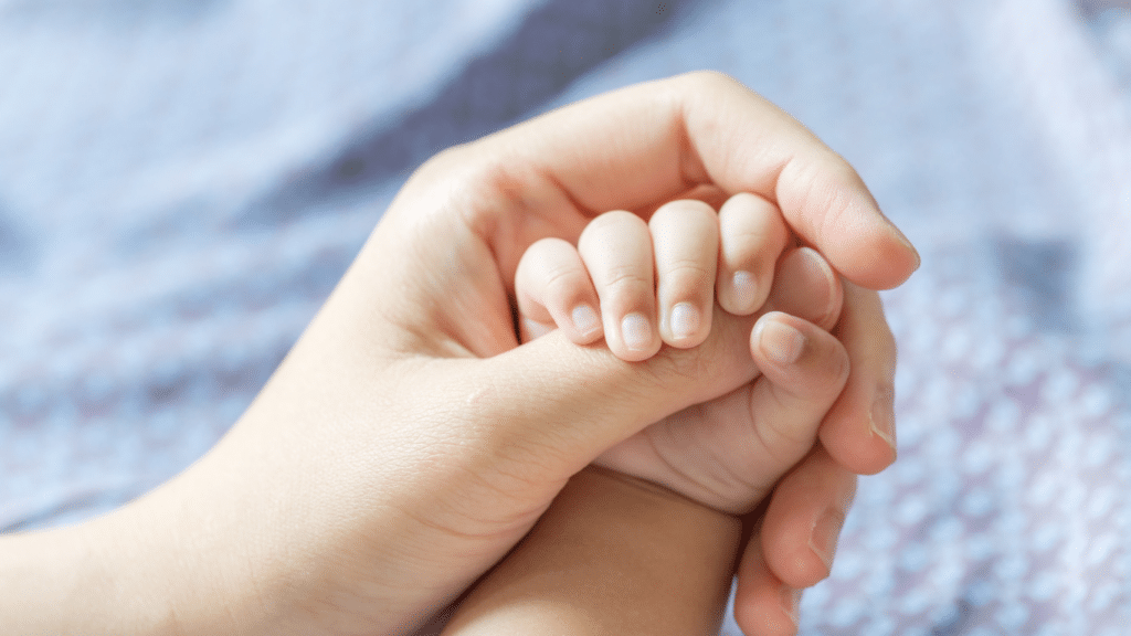 Baby's tiny hand holding onto mom's hand.