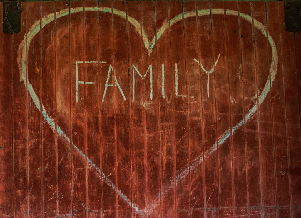 The word family is inside a heart carved on wood.