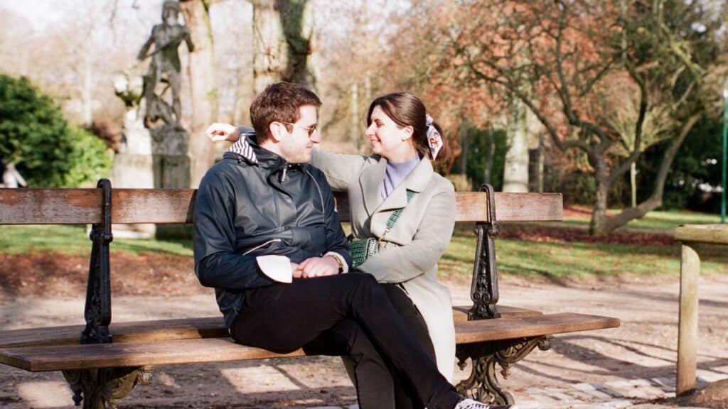 A couple sitting on a park bench, gazing into each other's eyes.