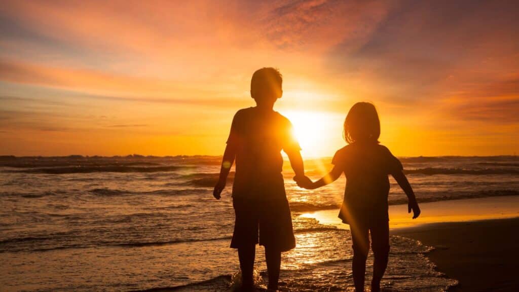 Two children holding hands at the beach.