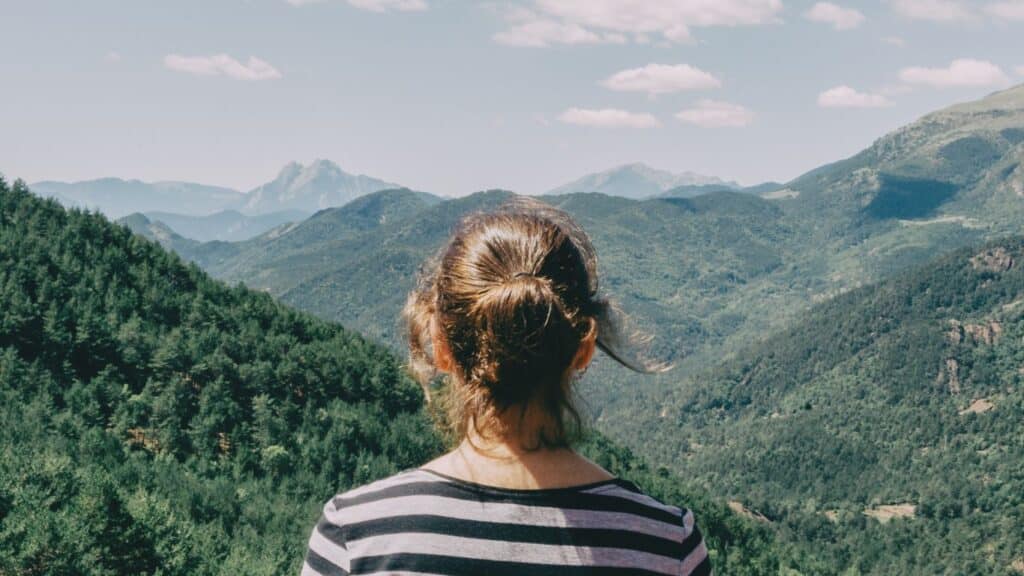 The back of a young girl looking at the mountains.