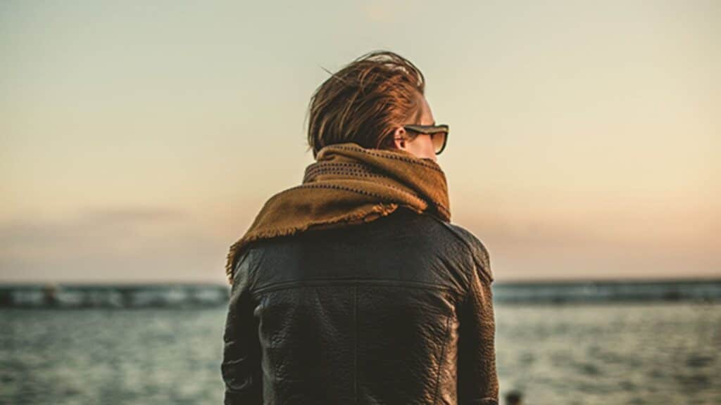 The silhouette of a young person gazing at the ocean.
