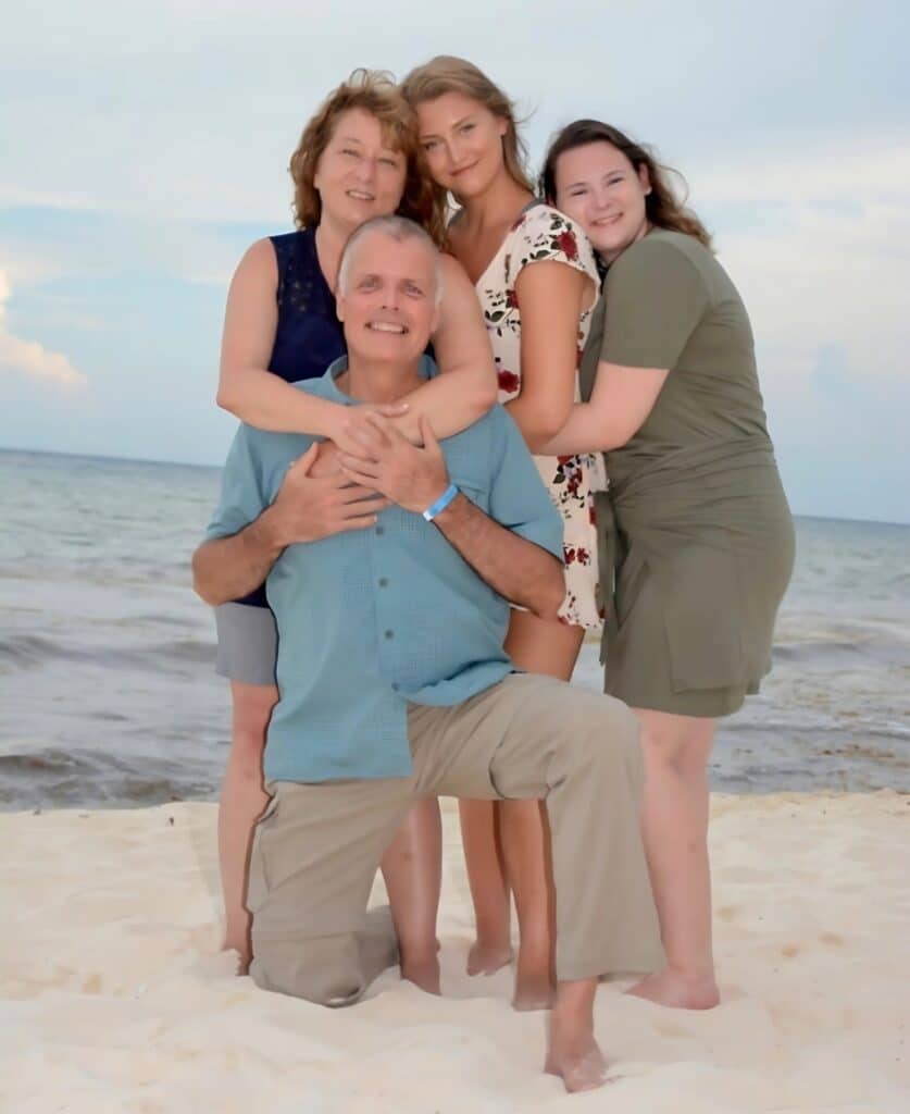 Desaray and her family posing together on a beach with the ocean in the background.