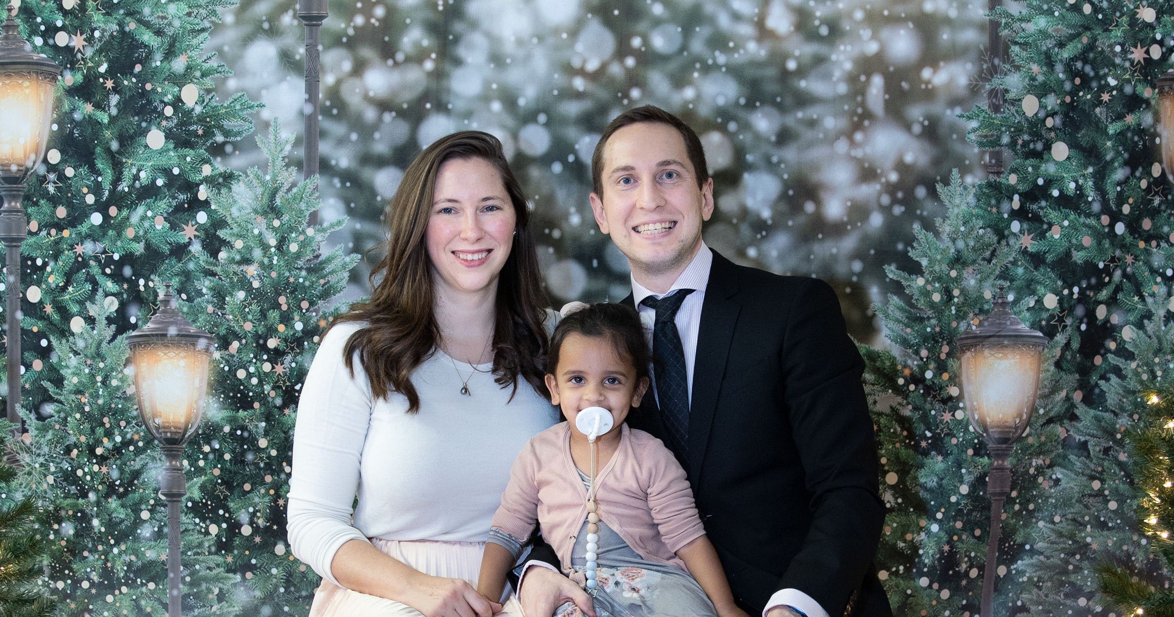 The Matthews family smiling for a photo against a snowy, festive Christmas backdrop.