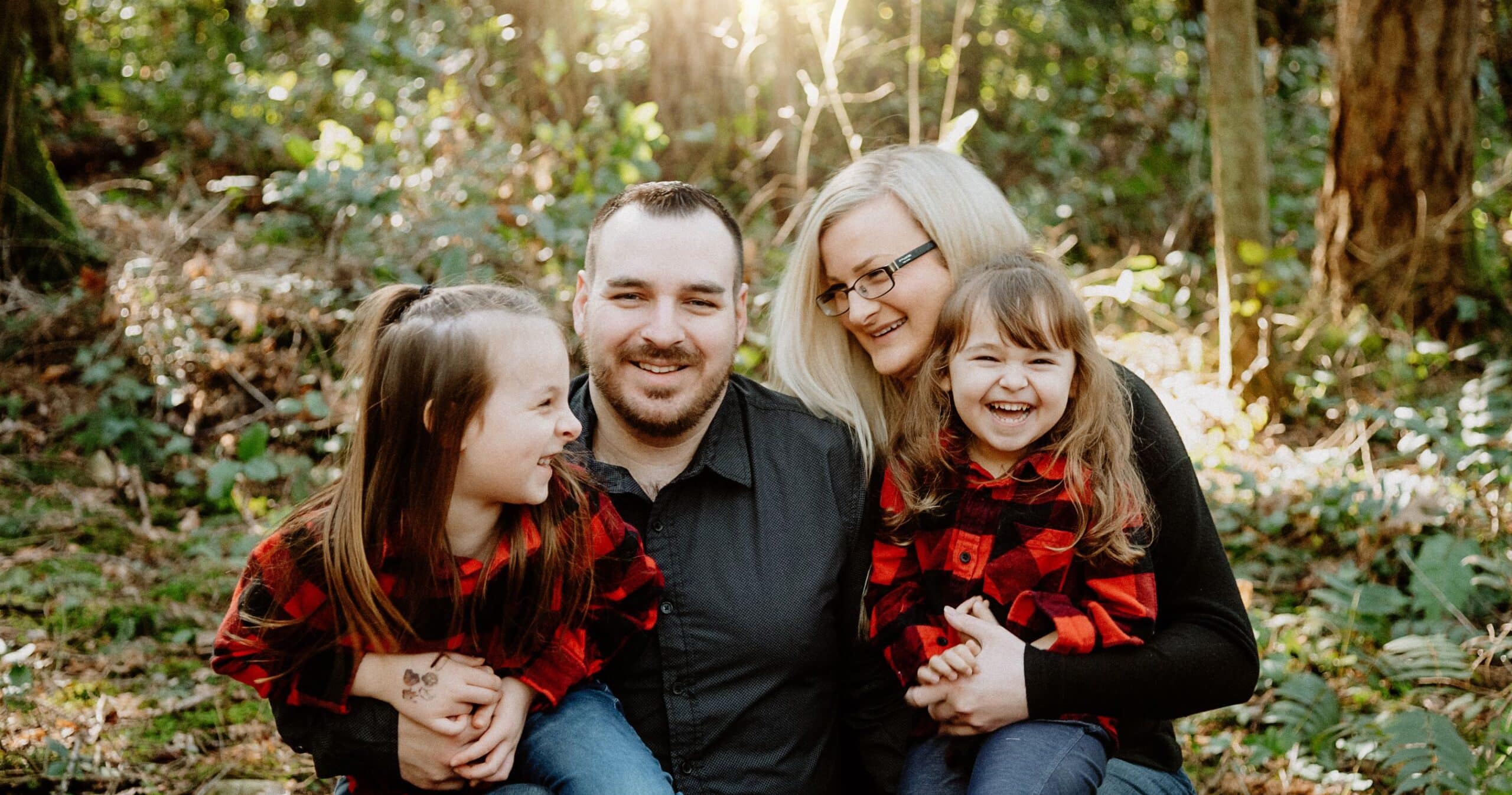 A family with two young girls wearing matching red striped shirts.
