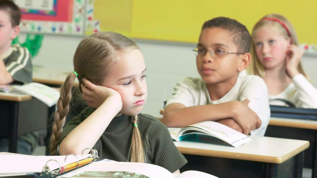 A girl in a classroom with a sad look on her face.