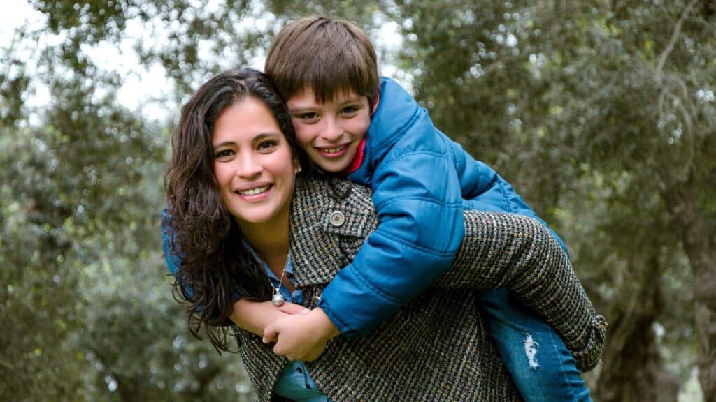 A mom giving her teenage son a piggyback ride.