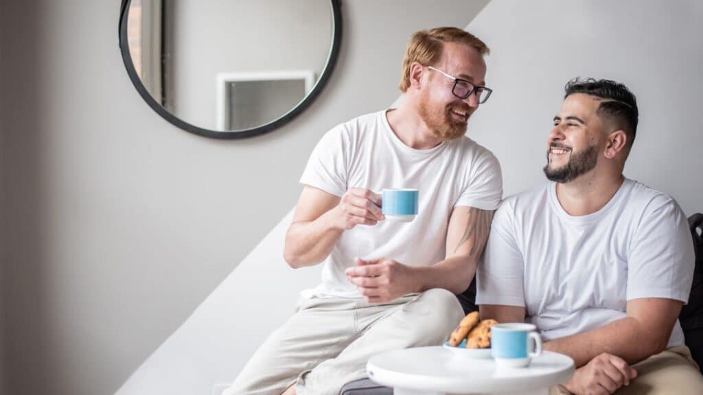 Two partners enjoying coffee together and sharing a warm smile.